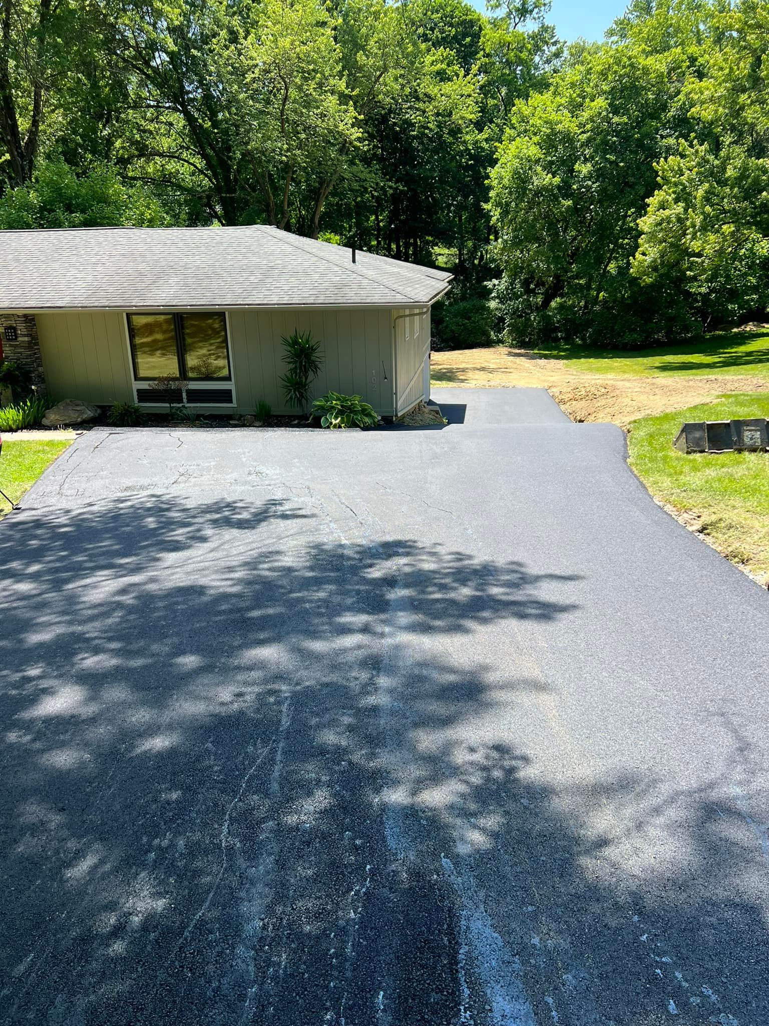 A driveway leading to a house with trees in the background.