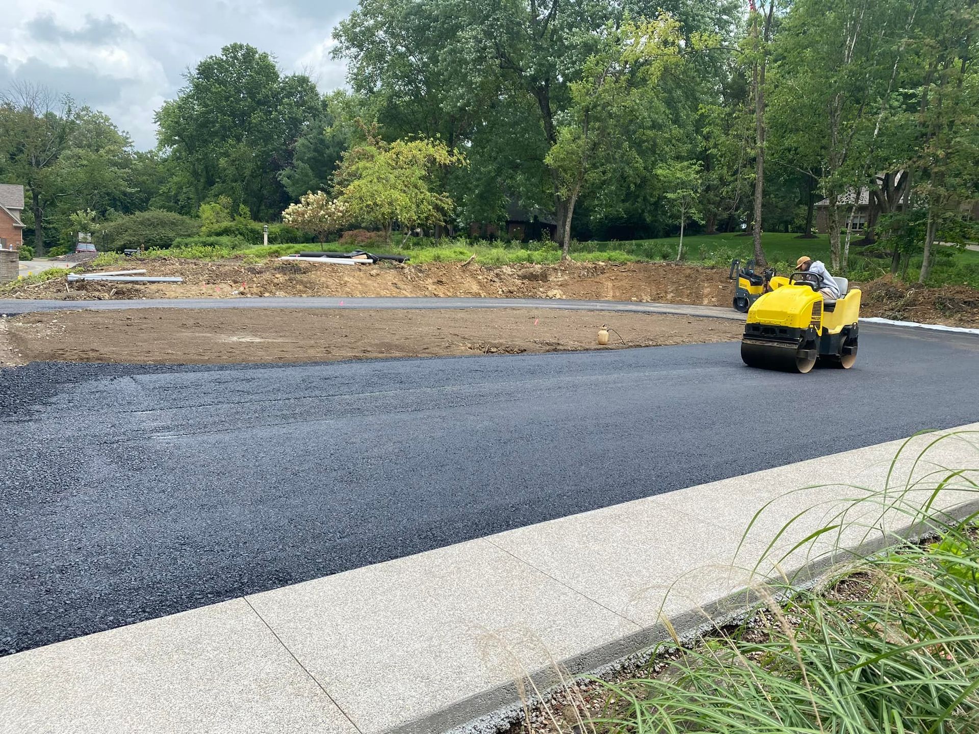 A yellow roller is rolling asphalt on a road.