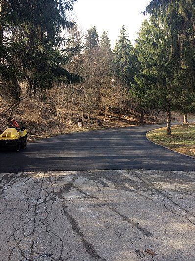 A yellow vehicle is driving down a road in the woods.