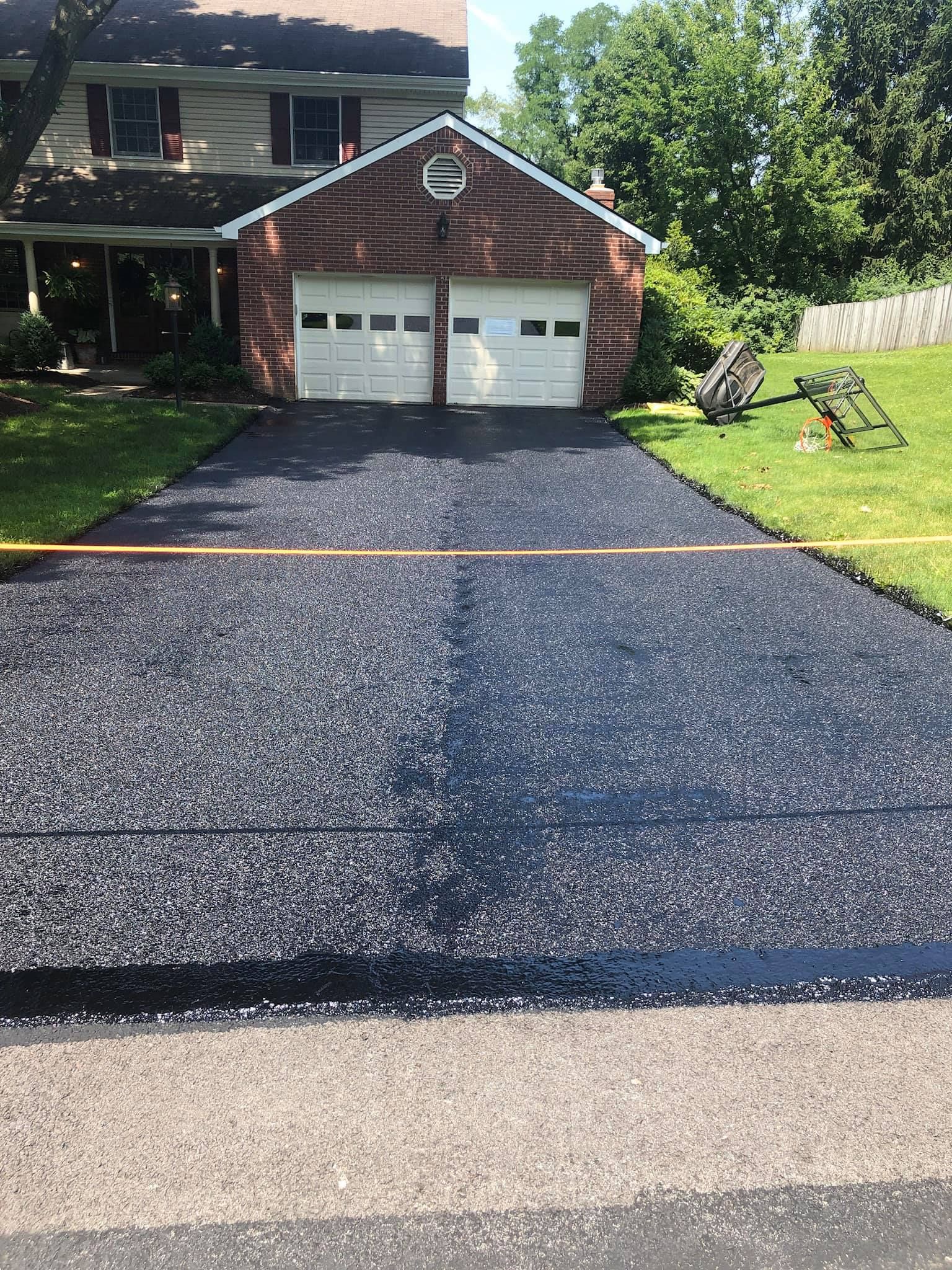 A driveway is being paved in front of a brick house.