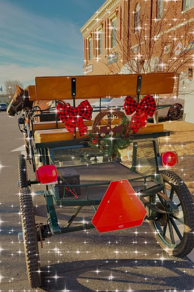 A horse drawn carriage decorated with hearts and bows is parked on the side of the road.