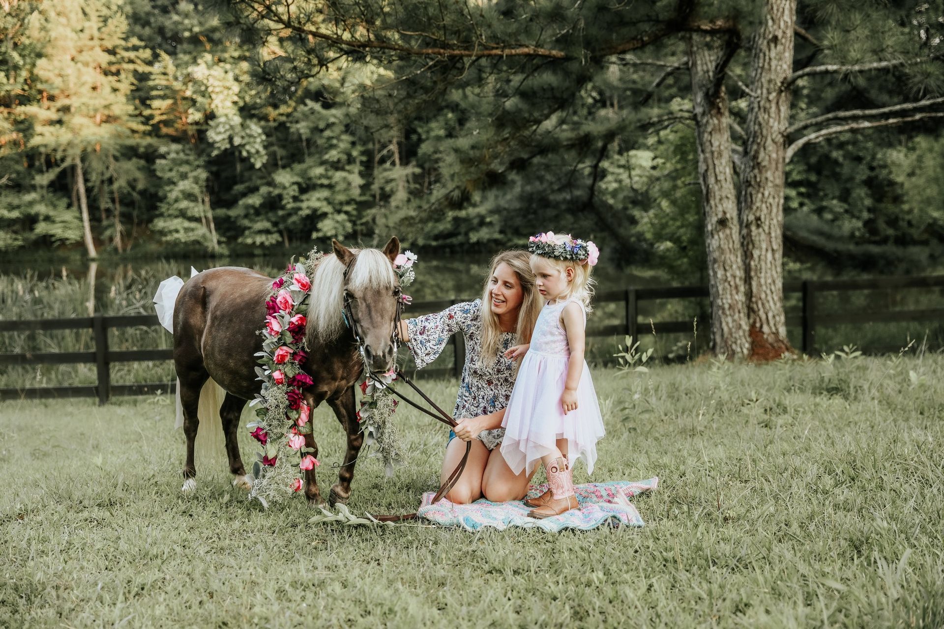A woman and two girls are sitting on a blanket next to a horse.