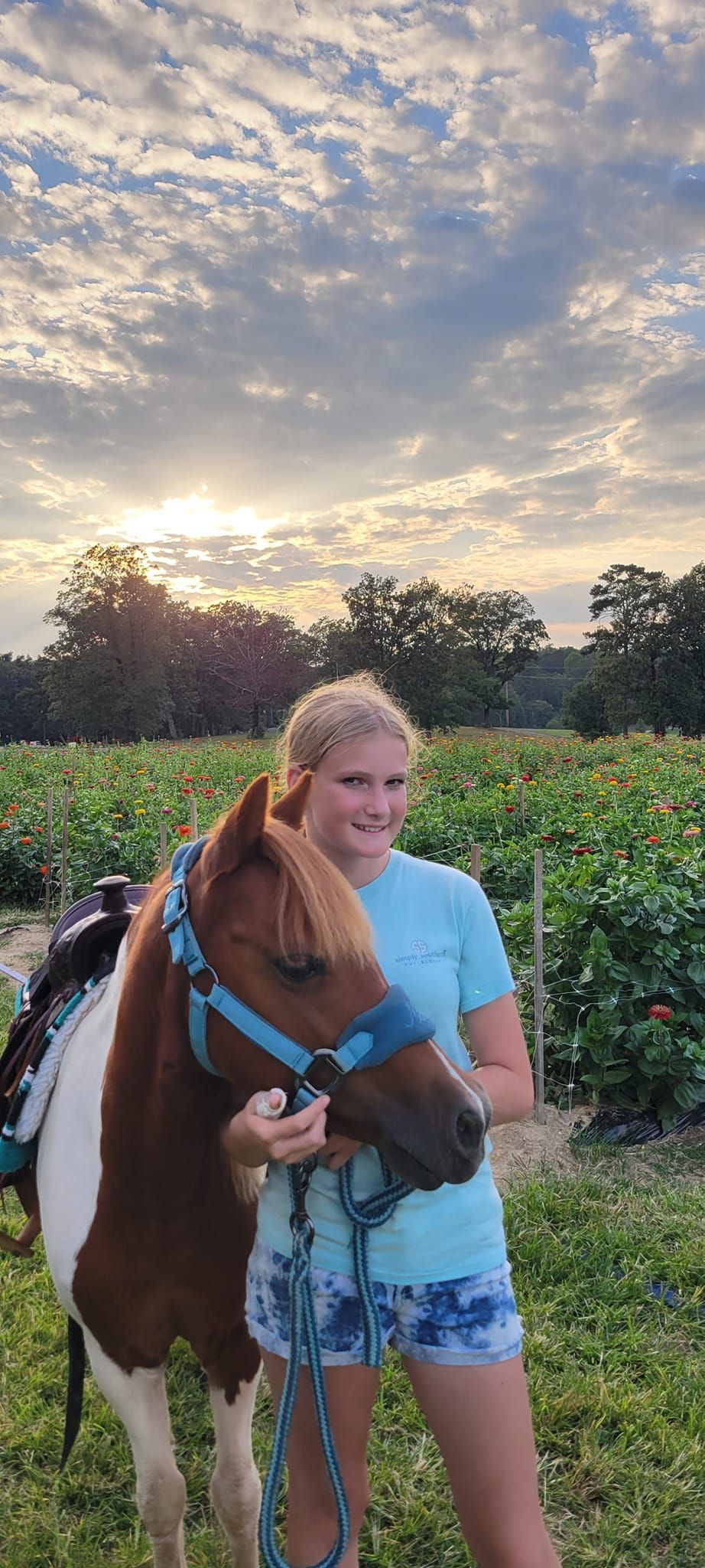A woman is standing next to a brown and white horse in a field.
