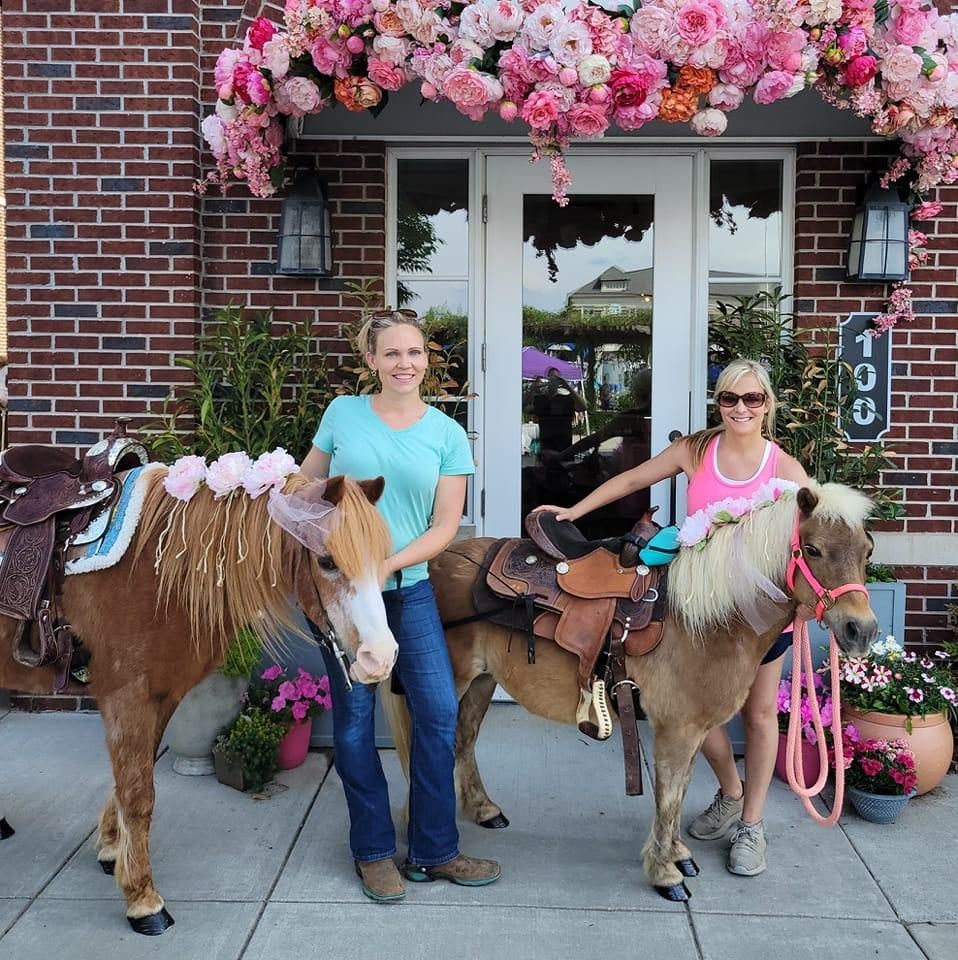 Two women standing next to a horse with a saddle on it