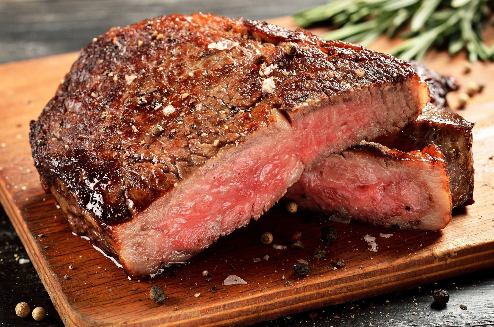 Sliced, juicy steak on a wooden board, with pink interior and seasoned crust.