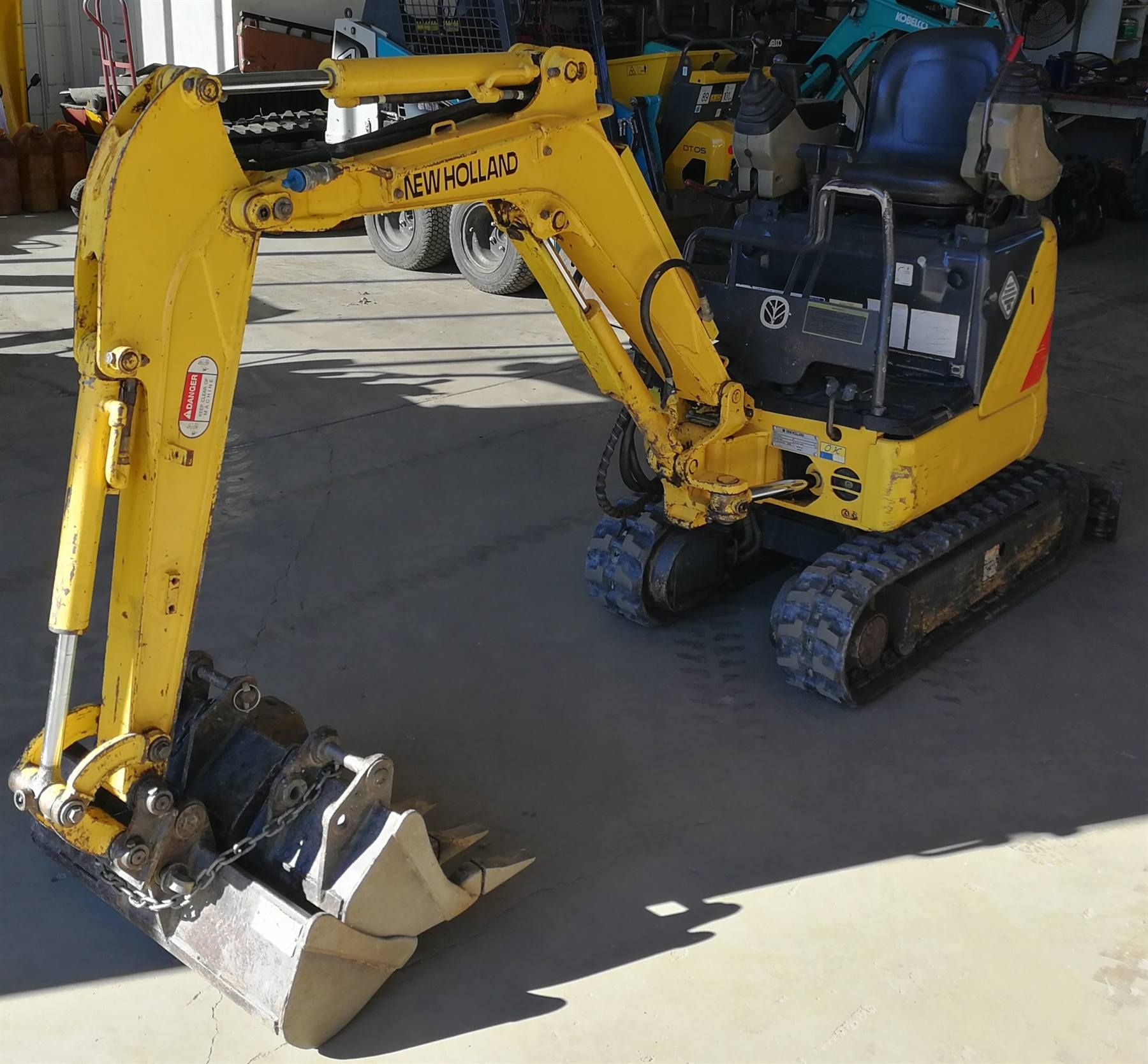Yellow Komatsu mini excavator on tracks, parked indoors.