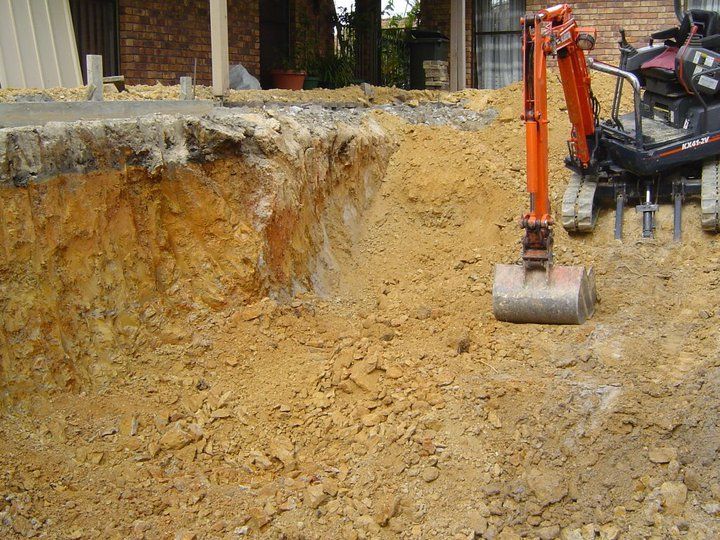 Mini excavator in a construction site digging into the earth.