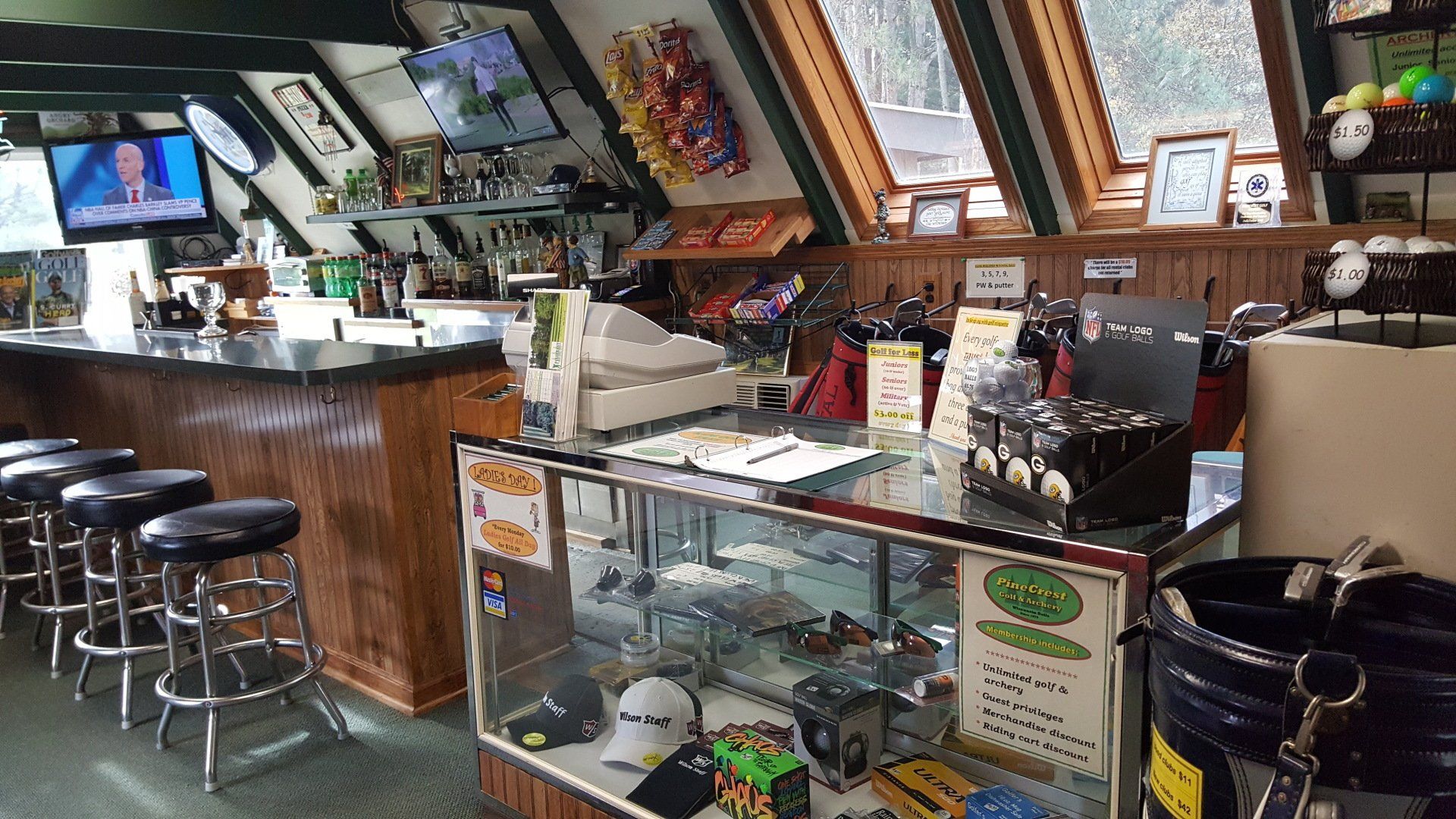 a restaurant with a bar , stools , a display case and a television .