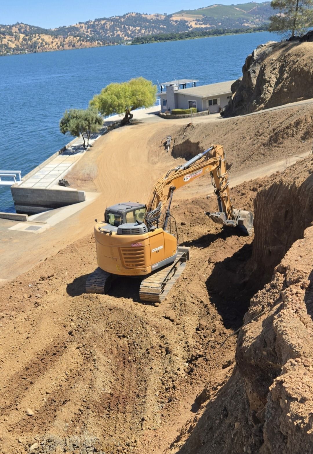Yellow and black mini trencher digging a trench in brown soil.