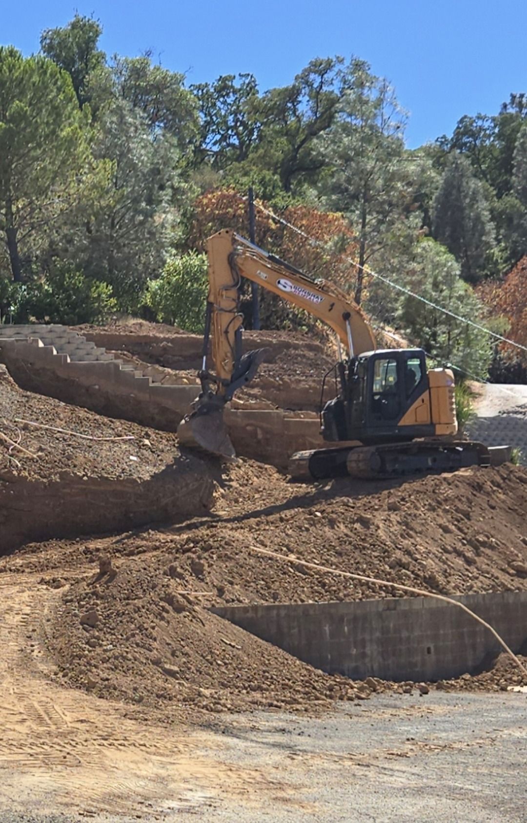 Yellow excavator loading demolition debris into a dump truck, construction site.
