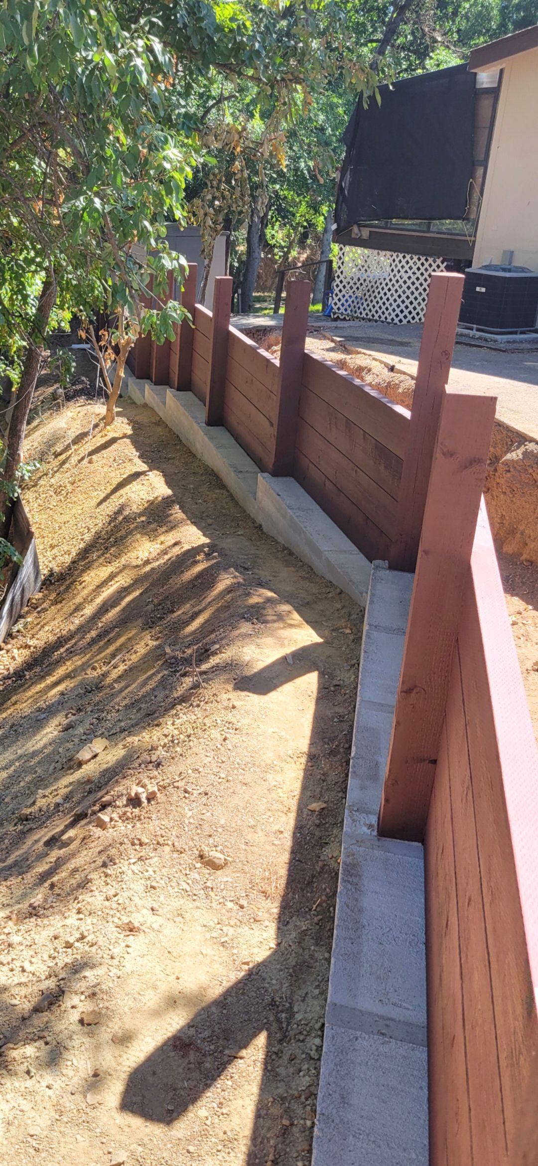 Man in safety vest placing concrete blocks on a gravel surface near a retaining wall.