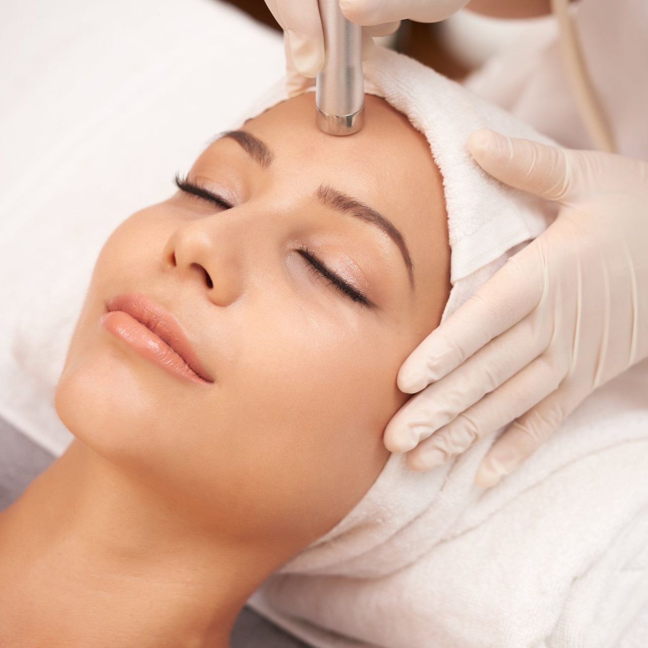 A woman with a towel on her head is getting a facial treatment