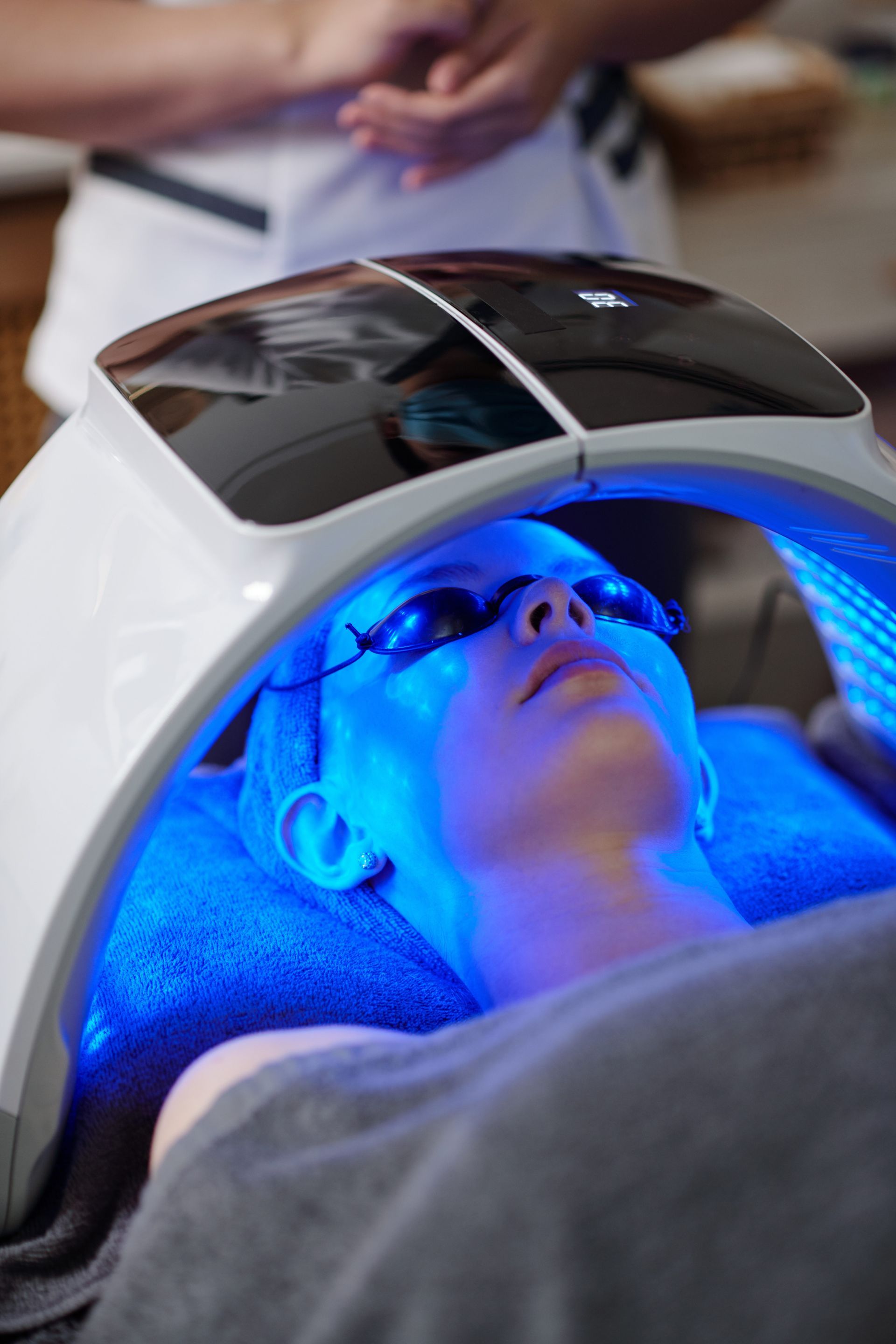 A woman is getting a blue light treatment on her face.