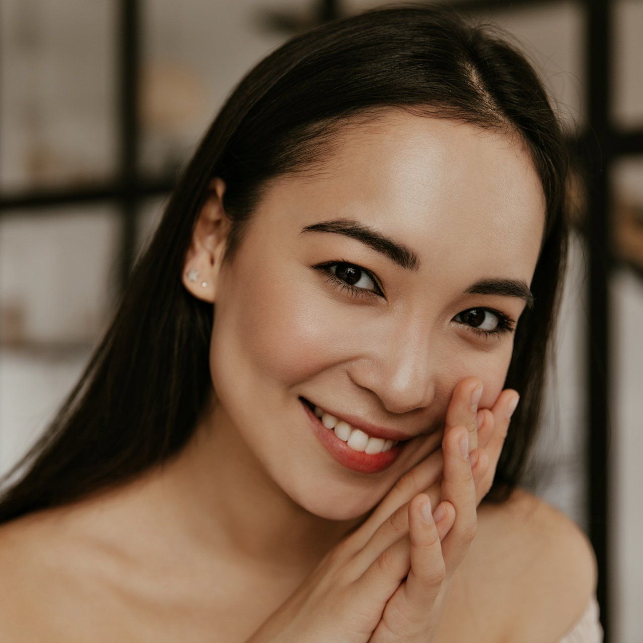 A woman is smiling and touching her face with her hand