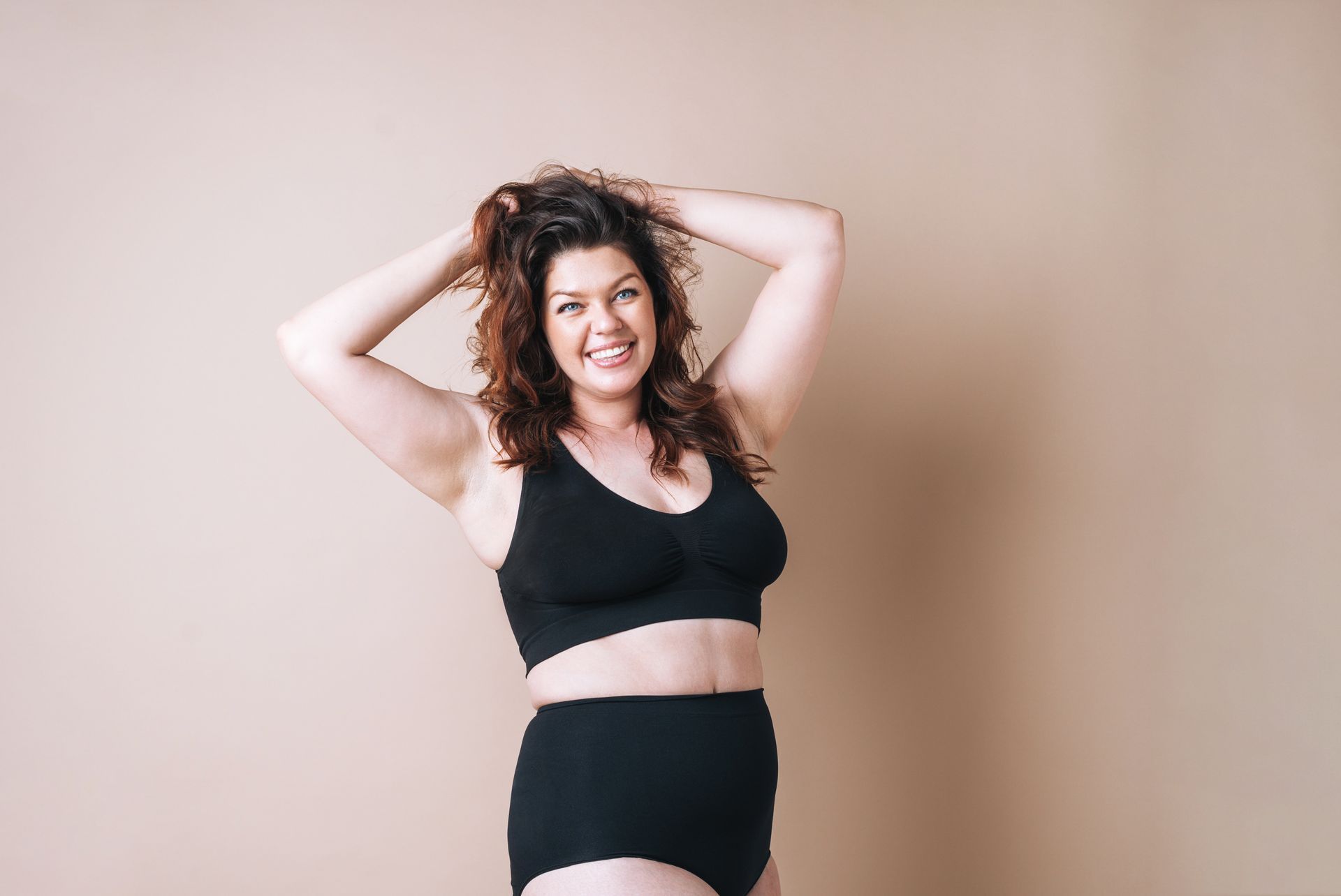 A plus size woman is wearing a black bra and underwear.