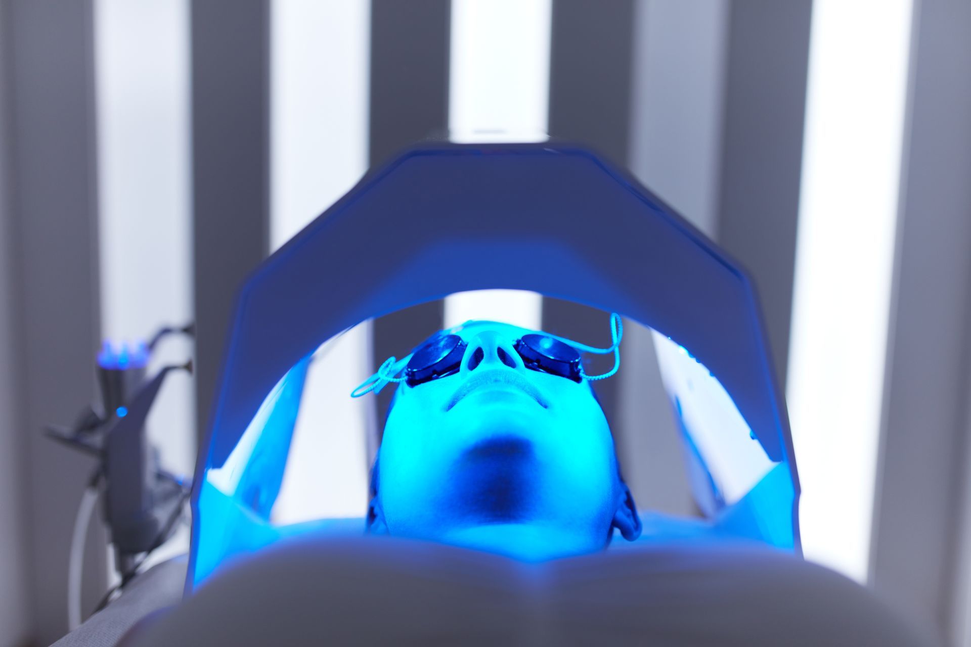 A person is getting a blue light treatment on their face.