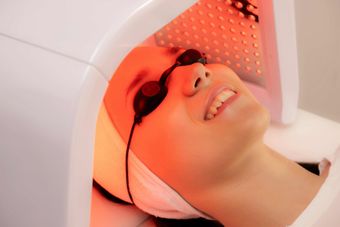 A woman is getting a red light treatment on her face.