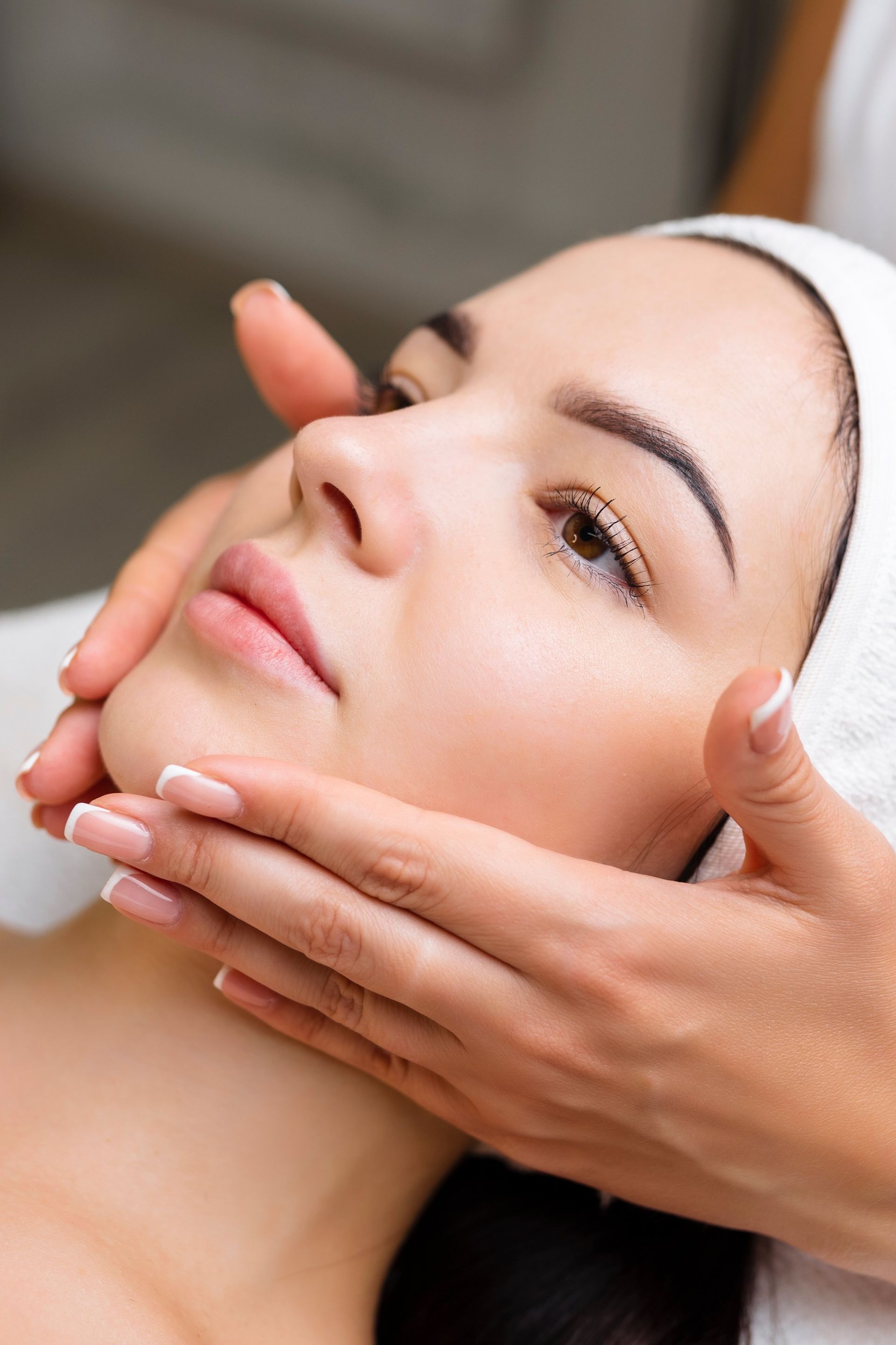 A woman is getting a facial massage at a spa.