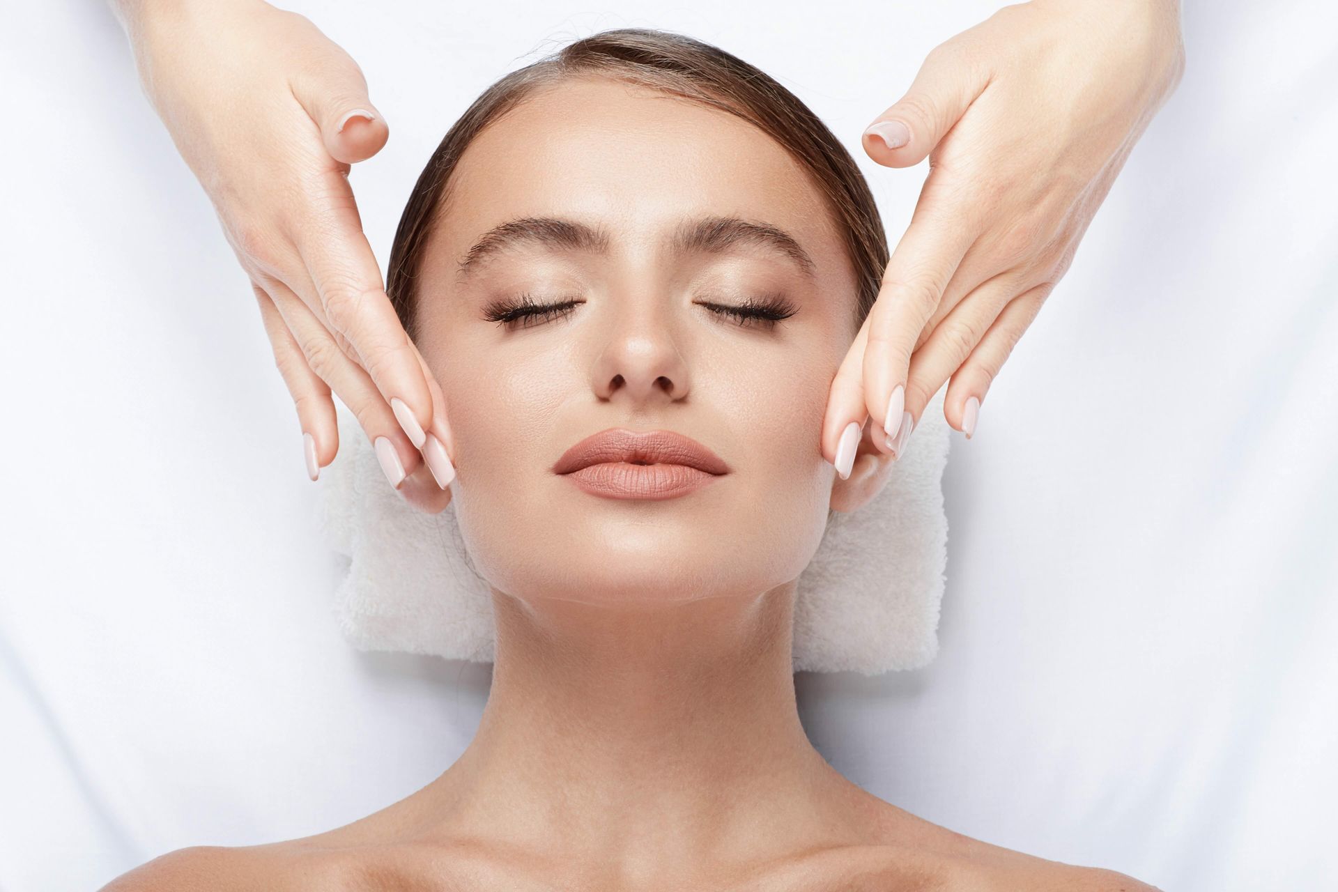 A woman is getting a facial massage at a spa.