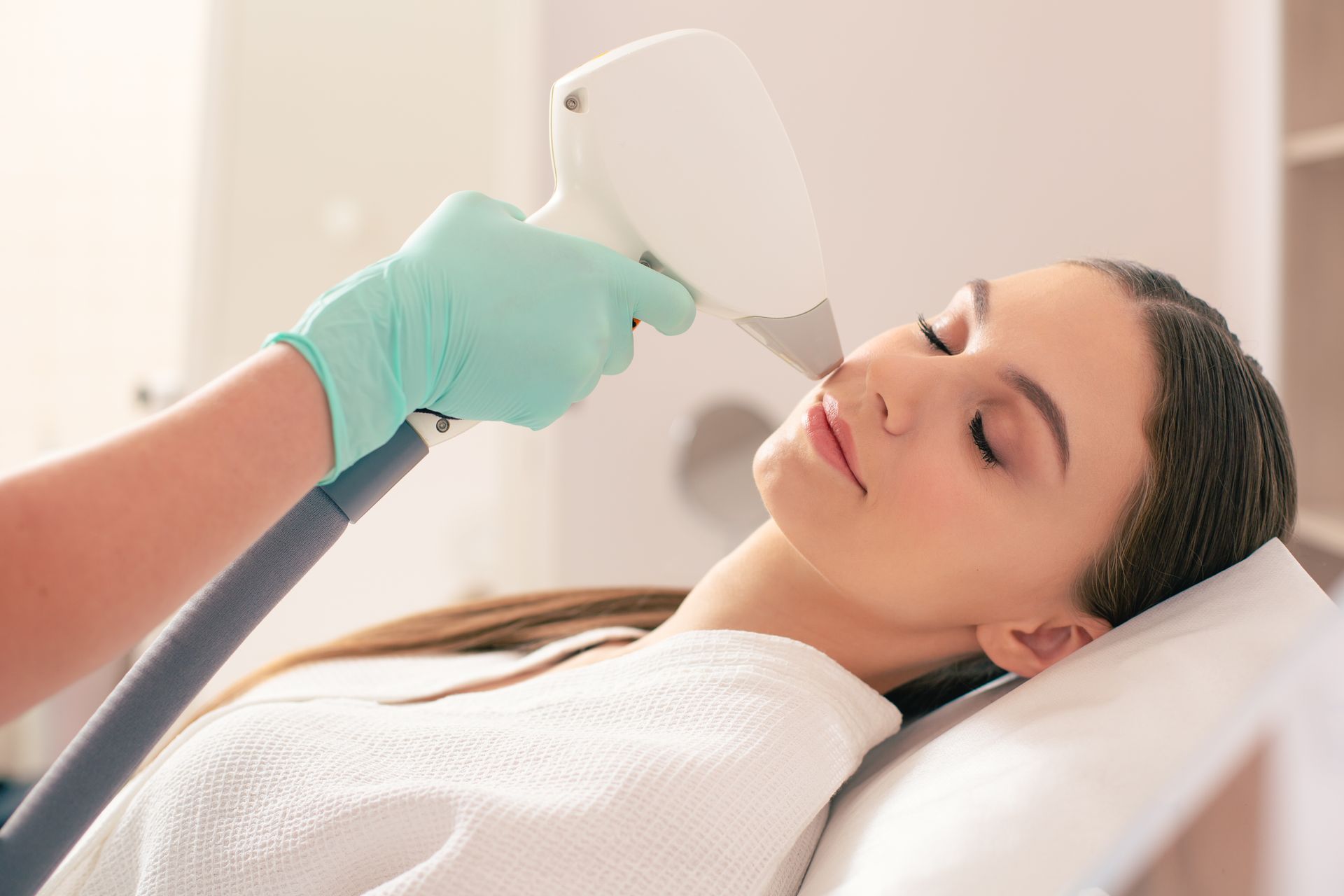 A woman is getting a laser hair removal treatment on her face.