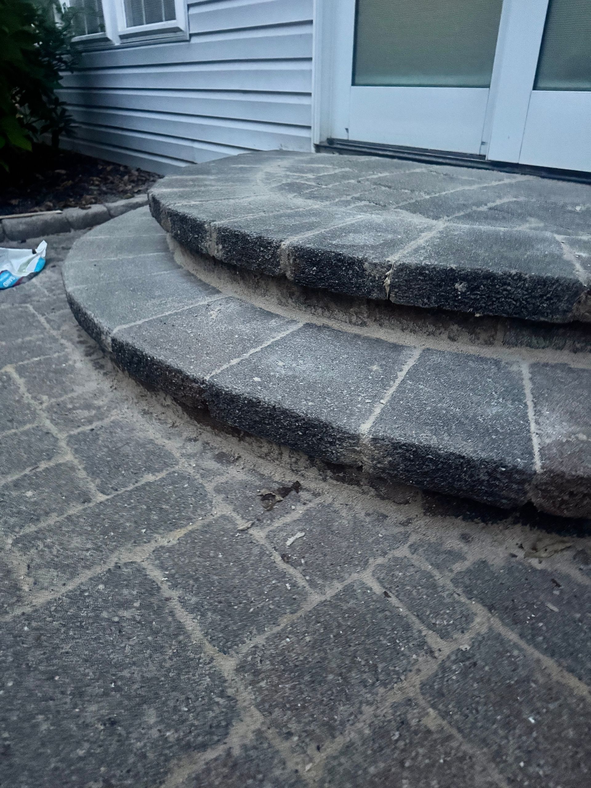Curved stone steps leading up to a white door, with matching brick walkway.