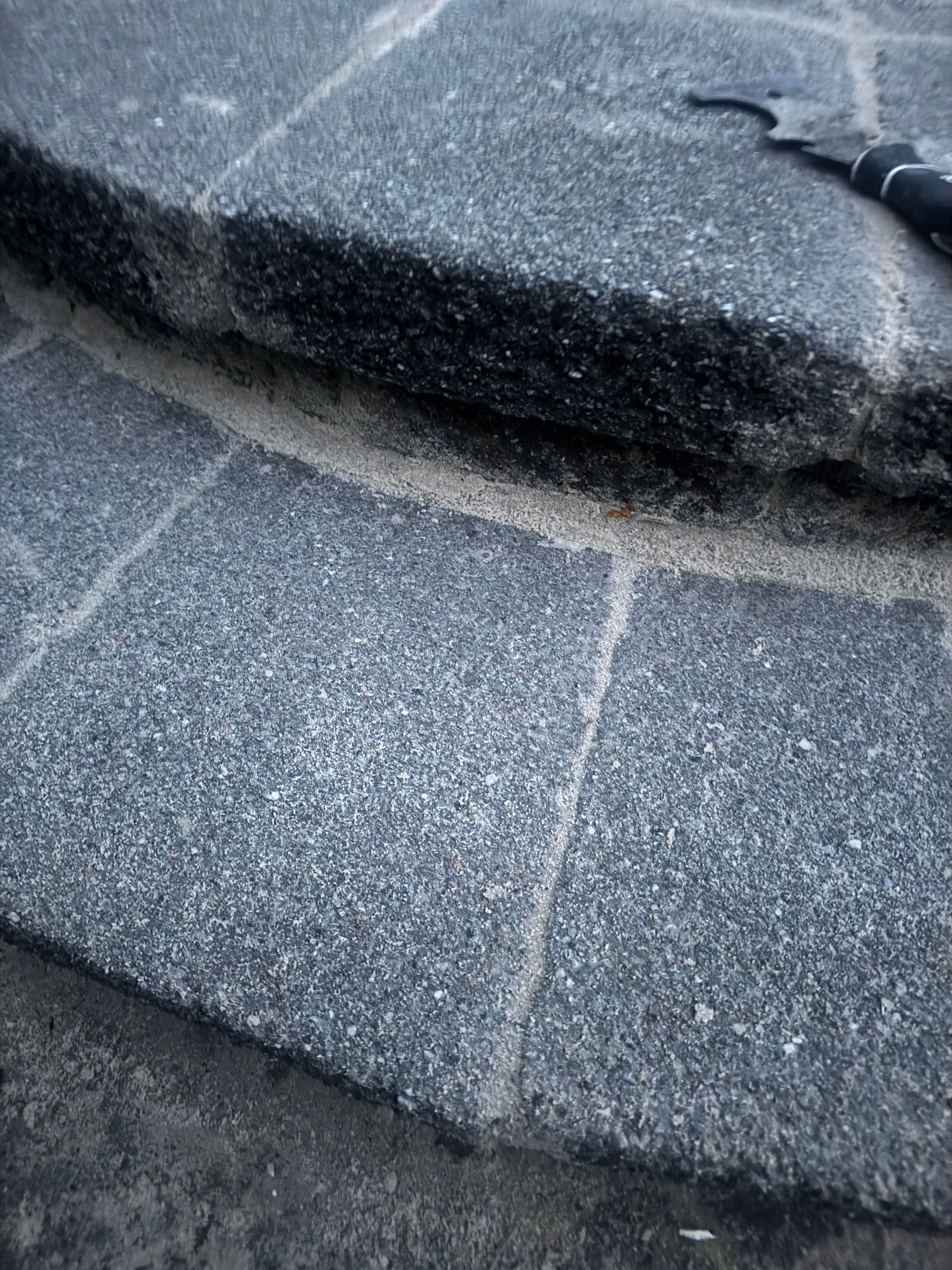 Close-up of circular stone steps with a tool resting on the top step.