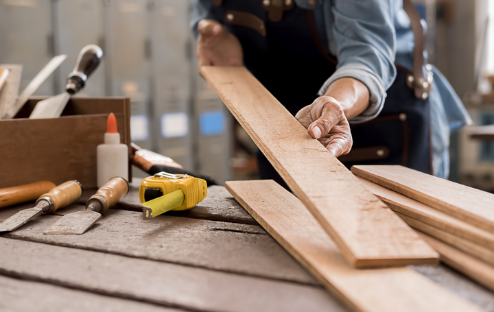 A person is cutting a piece of wood on a table.