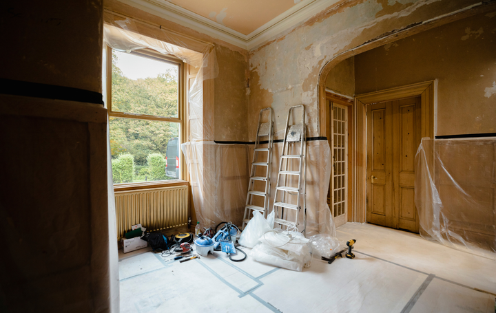 An empty room with a ladder and tools on the floor.