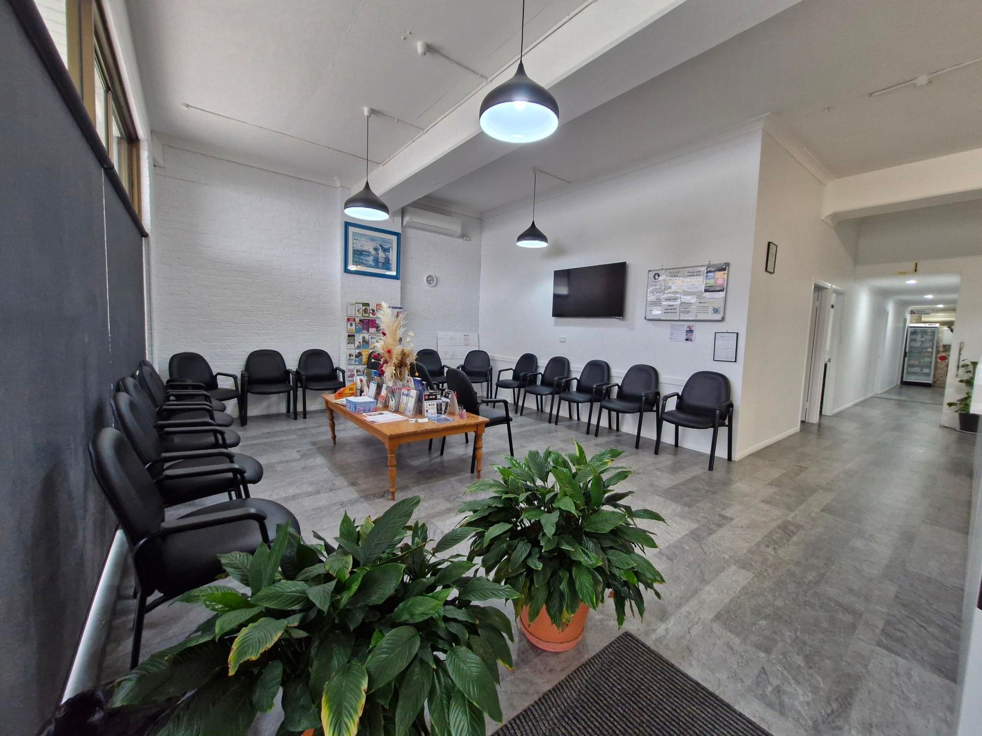 A Waiting Room with A Table and Chairs and A Tv on The Wall — Tuncurry Medical Centre In Tuncurry, NSW
