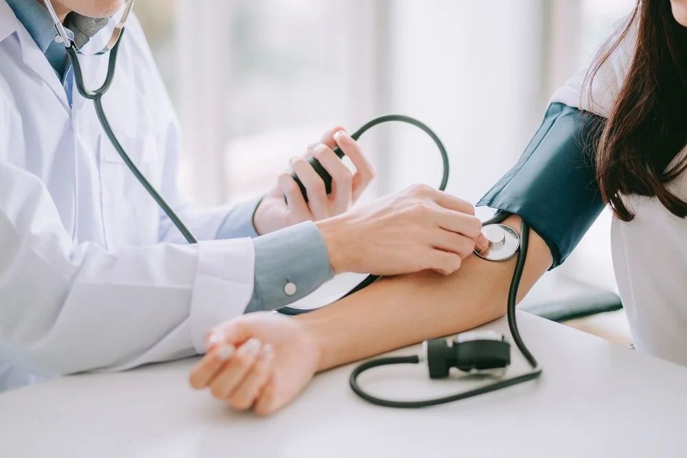A doctor checks a patient’s blood pressure using a sphygmomanometer and stethoscope during a medical examination — Tuncurry Medical Centre In Tuncurry, NSW