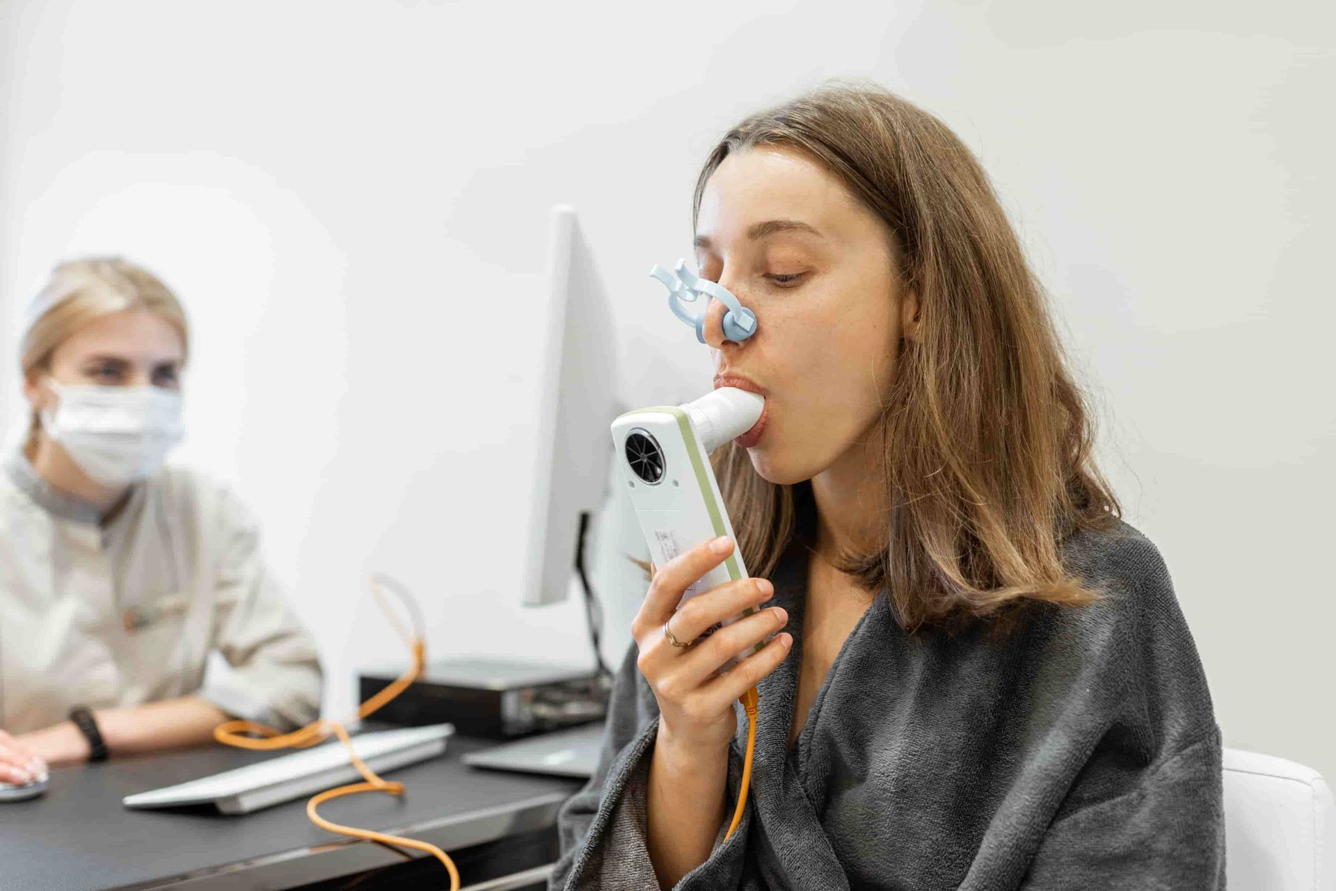 A Woman Is Wearing a Mask and Using an Inhaler — Tuncurry Medical Centre In Tuncurry, NSW