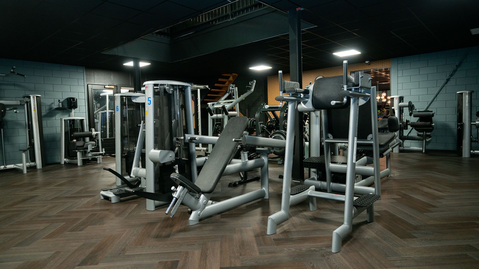 Een sportschool vol met fitnessapparatuur en een houten vloer.