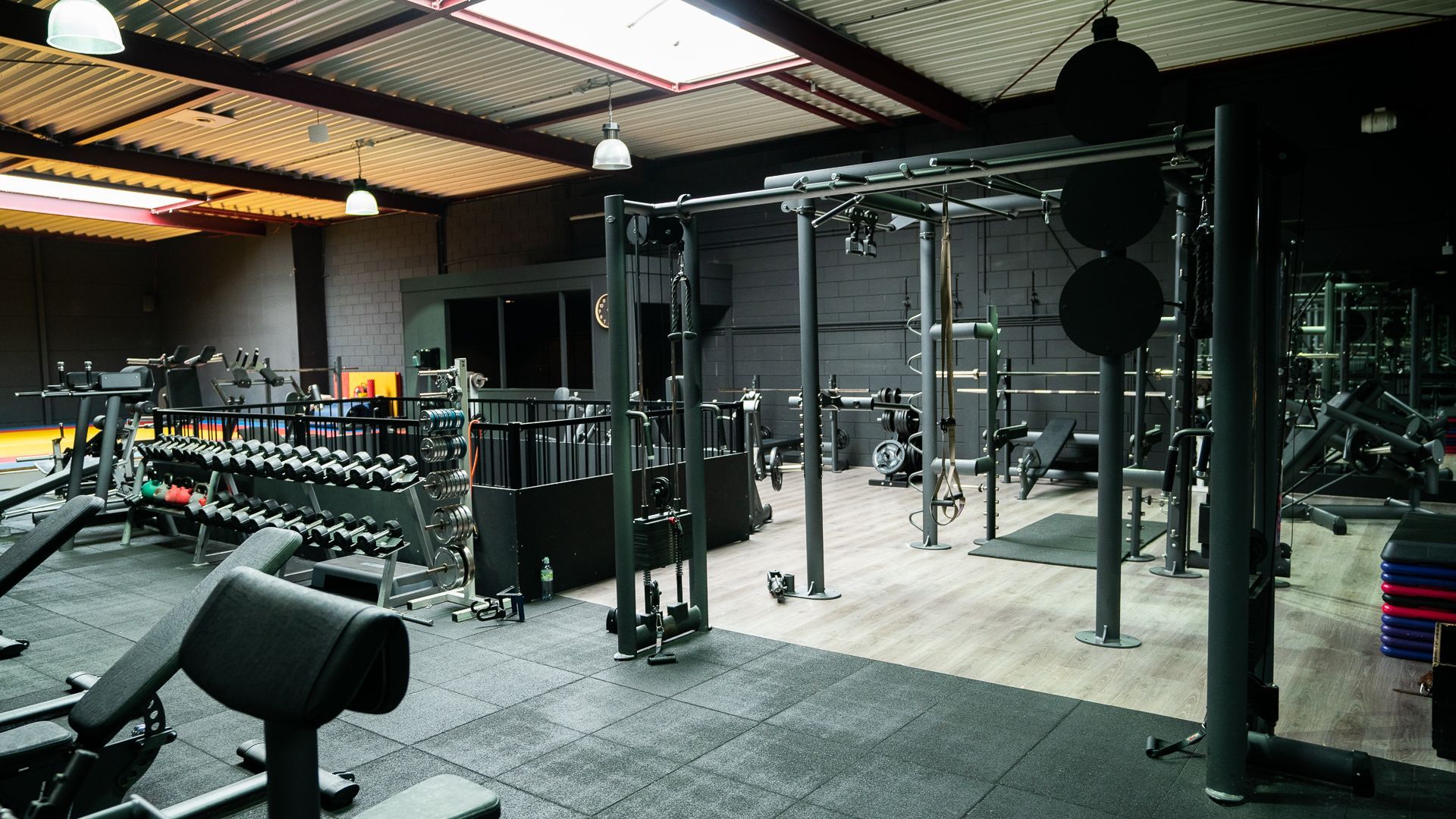 Een sportschool vol met fitnessapparatuur en een bank.