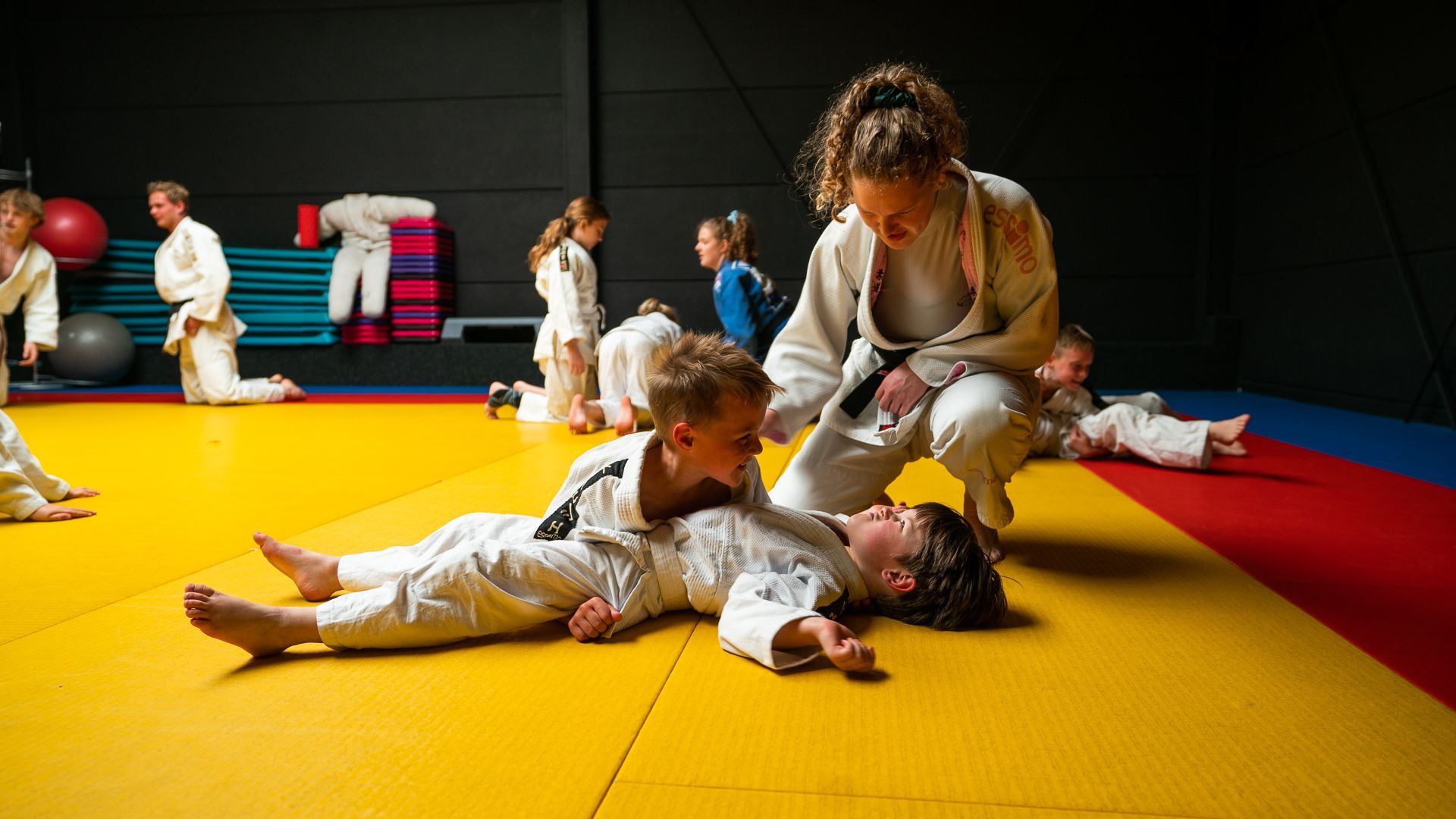 Een vrouw leert een jonge jongen judoën op een mat.