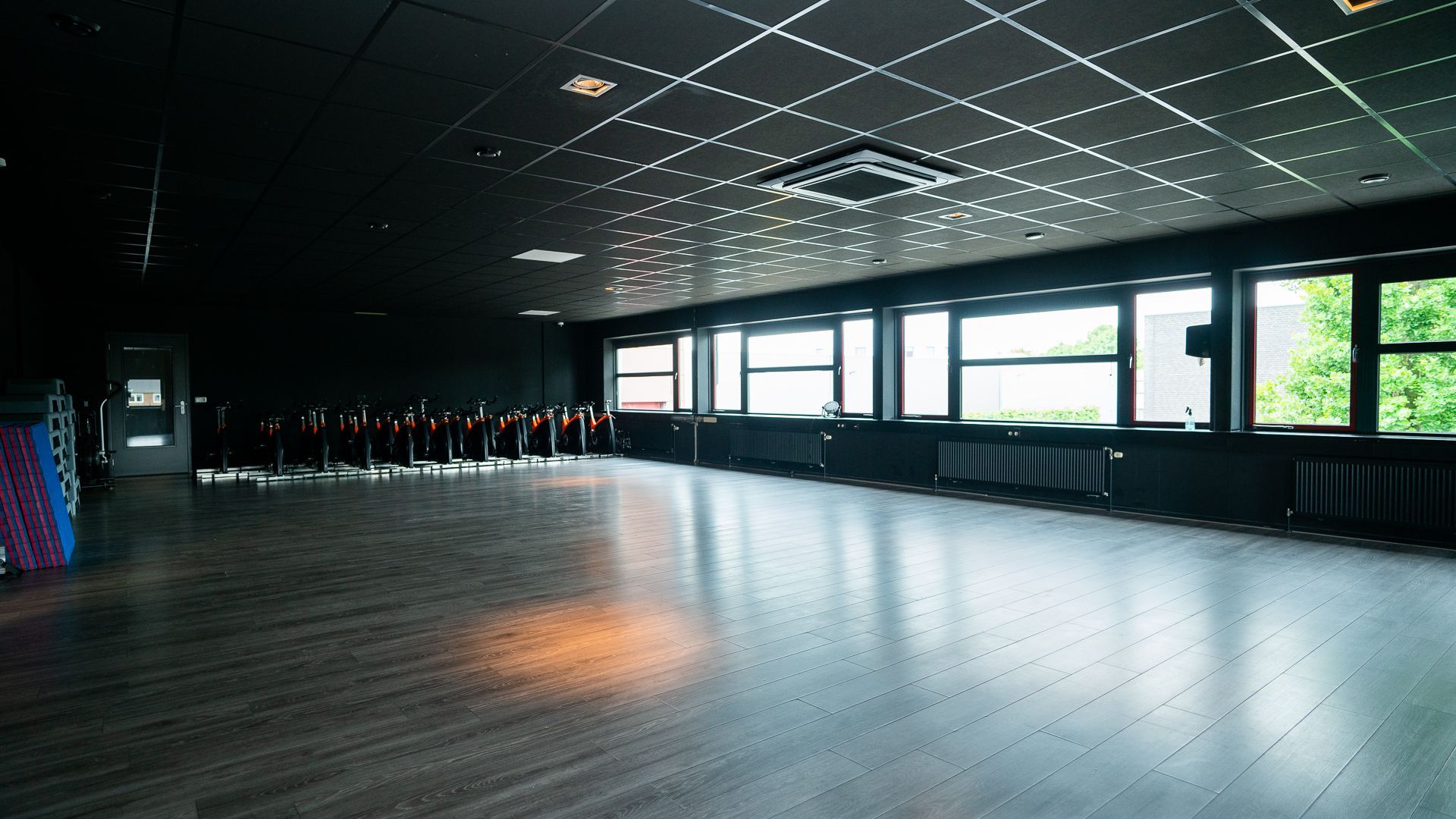 Een vrouw staat voor een groep mensen die op een hometrainer fietsen.
