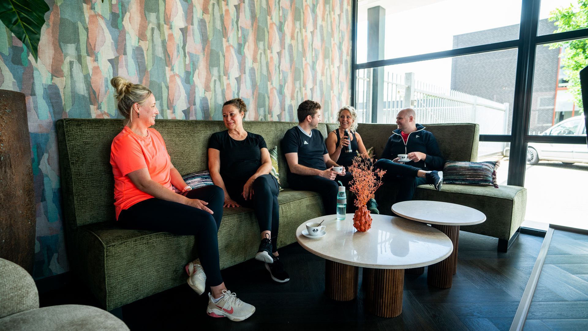 Een groep mensen zit op een bank in de woonkamer.