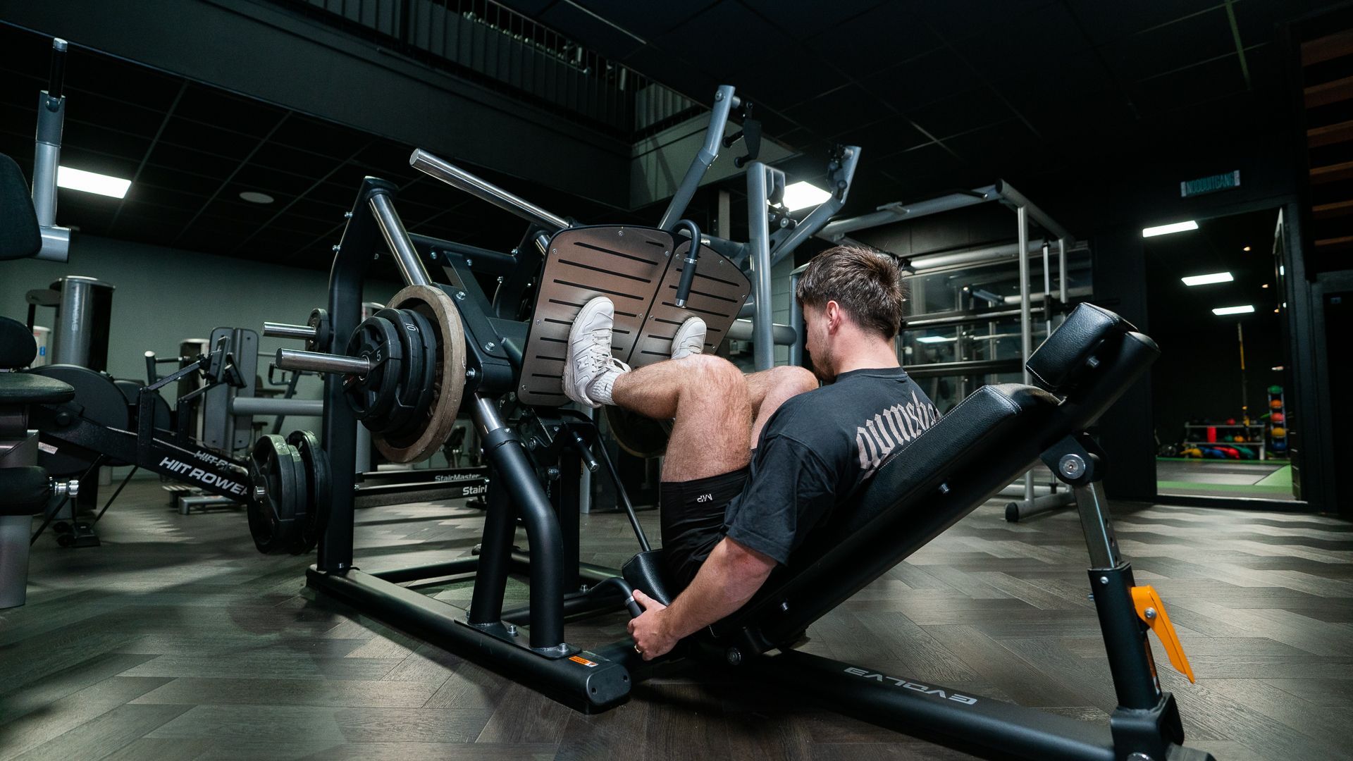 Een man helpt een vrouw met het tillen van halters in een sportschool.