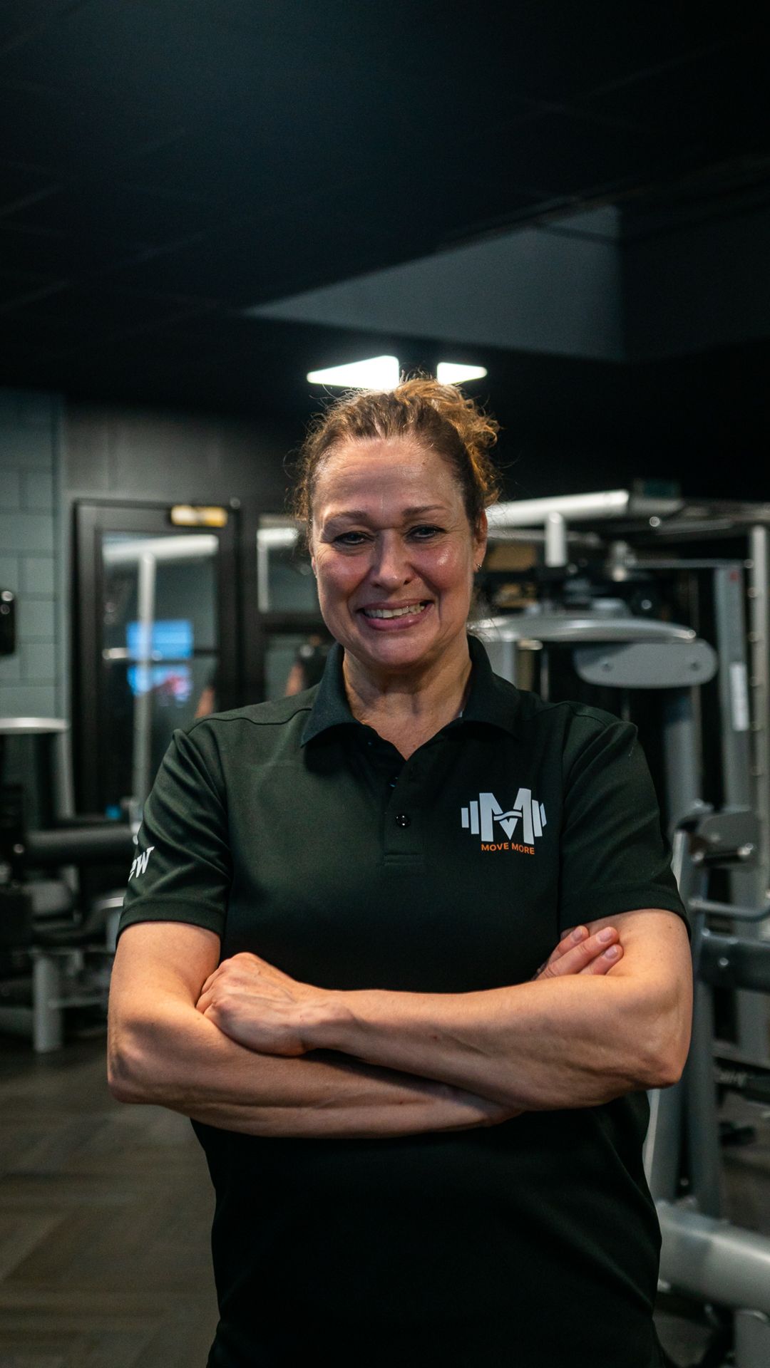 Een man in een zwart shirt staat met zijn armen over elkaar en lacht.
