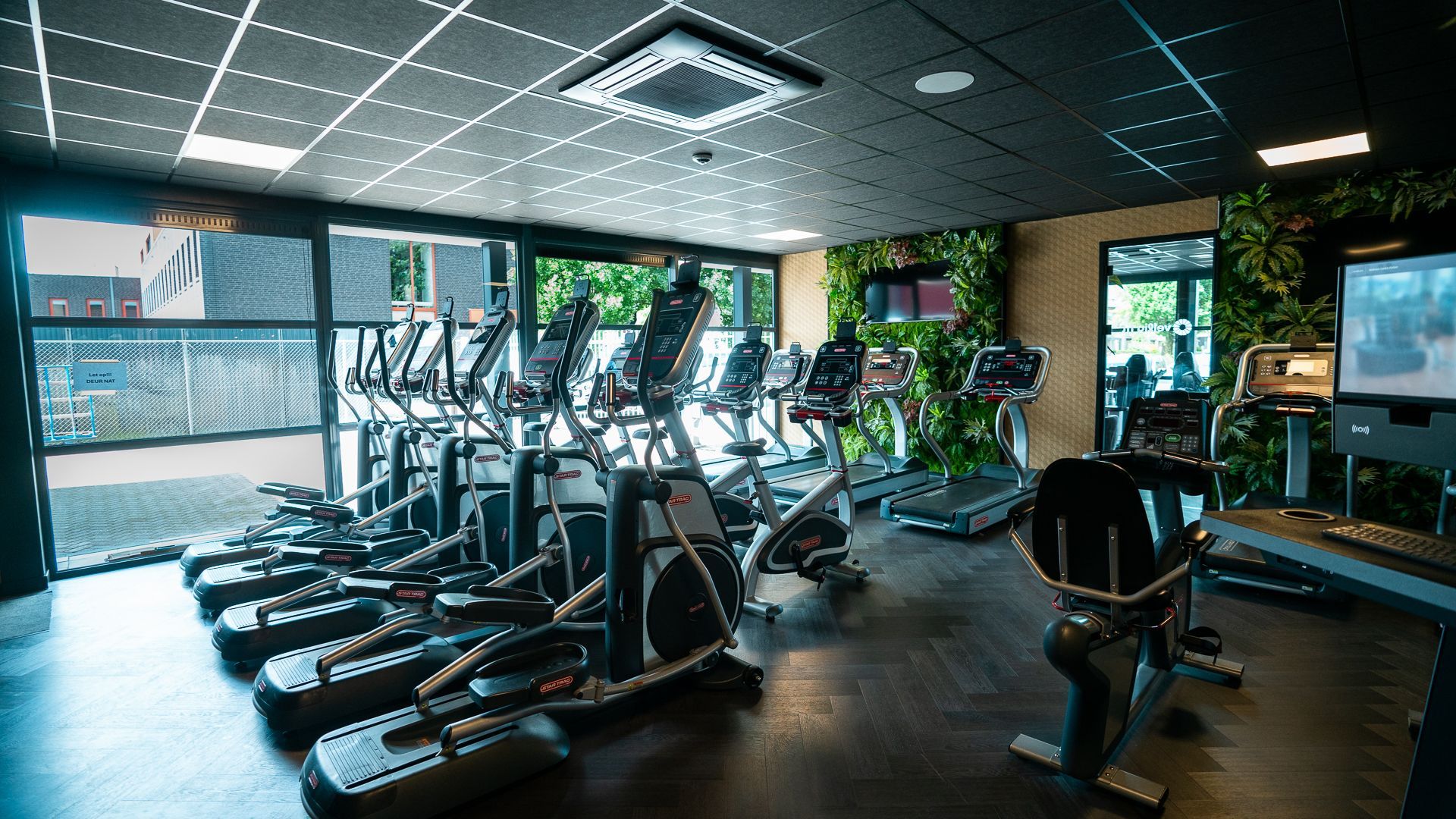 Een sportschool vol met fitnessapparatuur en een televisie.