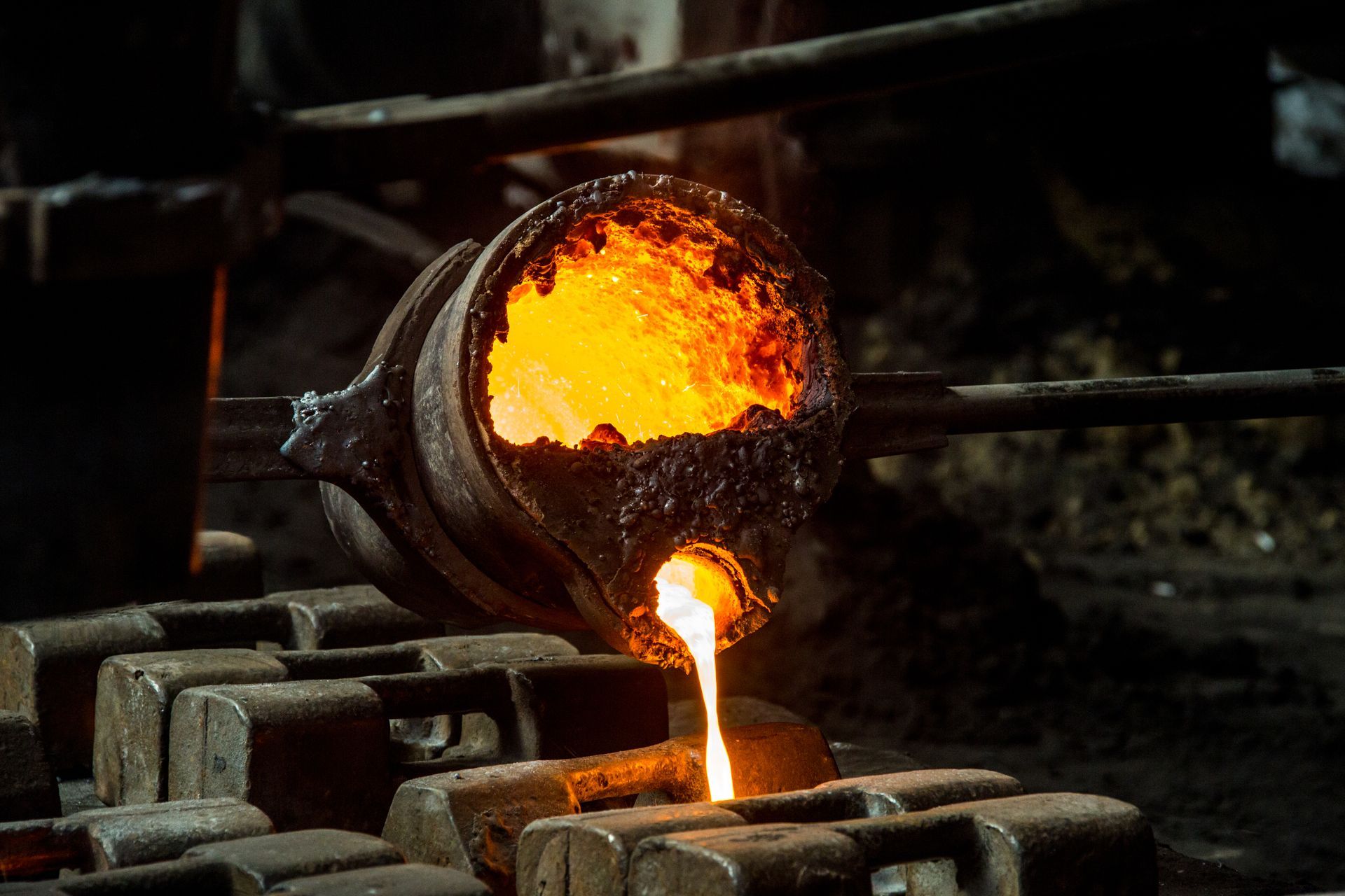 Pouring ingots of metal in metal foundry.