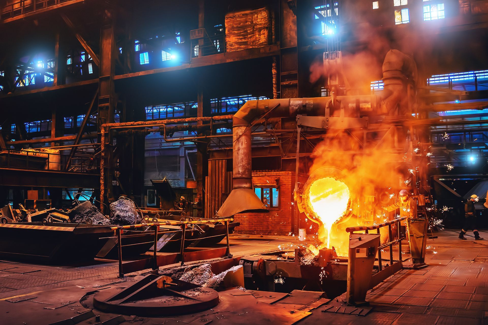 Molten metal pouring in a steel mill, bright orange and emitting sparks. Industrial setting with machinery.