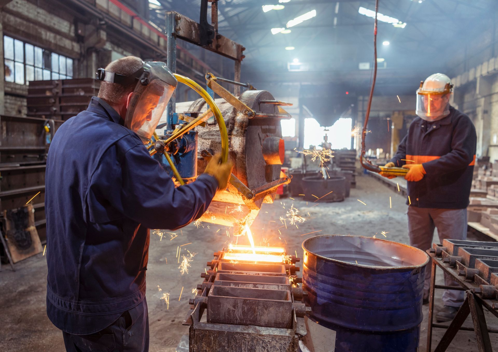 Workers pouring molten metal into mold in iron foundry. Workers pouring molten metal into mold in iron foundry.