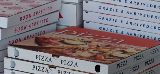 Stacks of pizza boxes, some with Italian phrases like