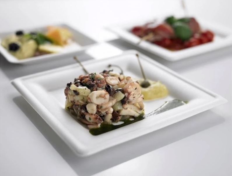 Tre piccoli piatti di cibo su una superficie bianca: insalata di polpo, un piatto di carne e un altro piatto.