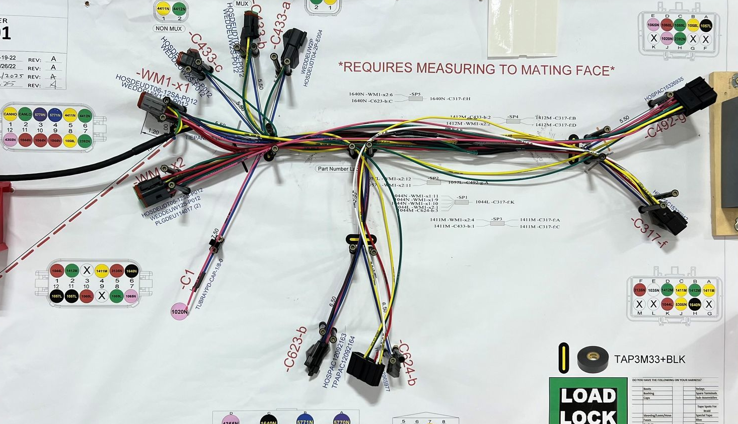 Close-up of a complex network of multicolored electrical wires, neatly bundled and secured within a gray panel.