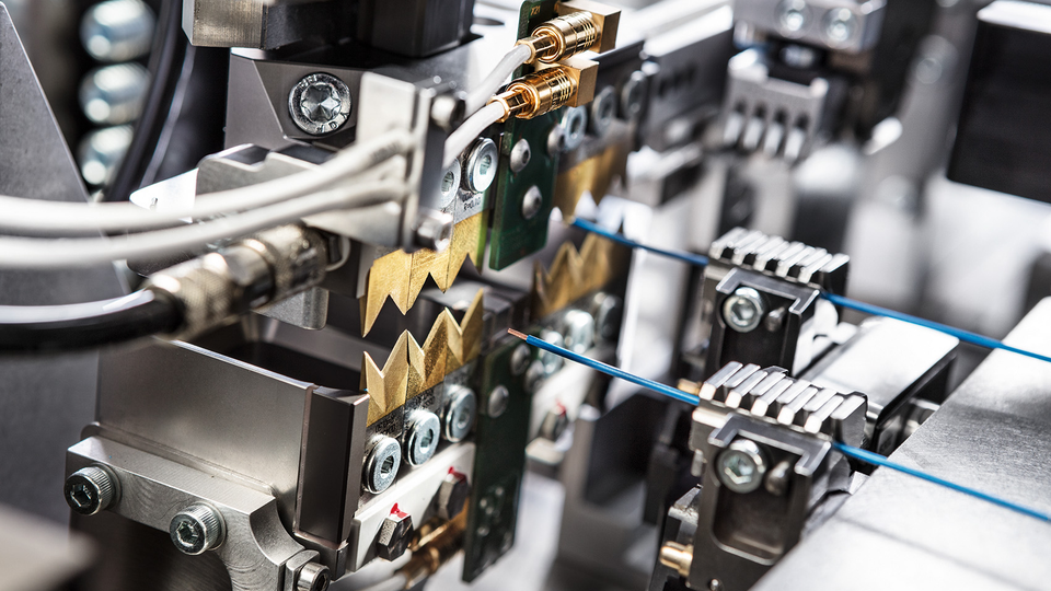 manufacturers standing and talking to each other in front of a wire processing machine
