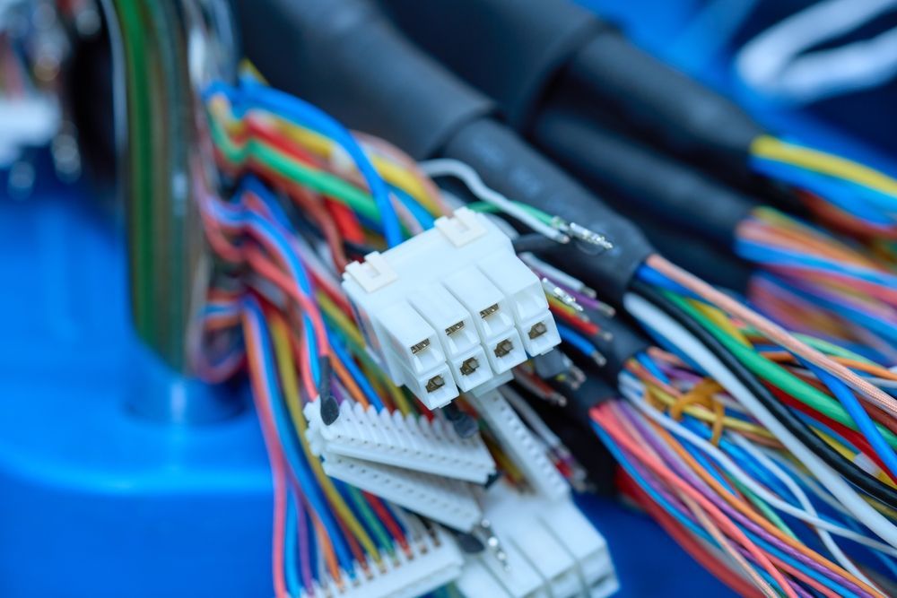 Close-up of a bundle of multi-colored electrical wires connected to several white plastic electrical connectors.