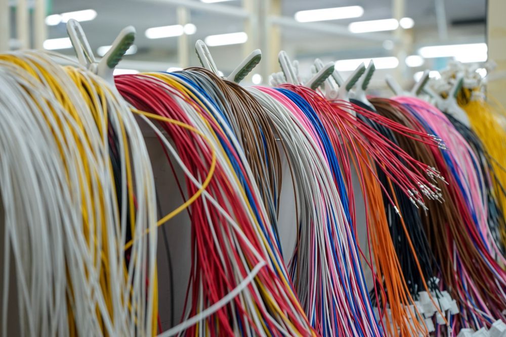 Colorful electrical wires hanging on metal hooks.
