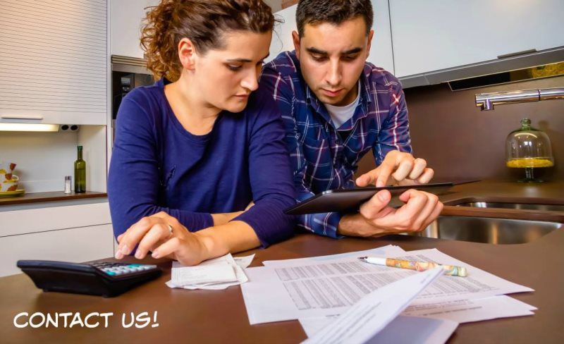 A man and a woman are sitting at a table looking at a tablet.