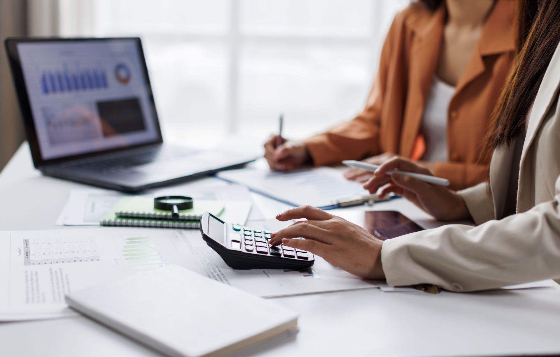 two people calculating debt payoff with laptop, calculator, and financial papers
